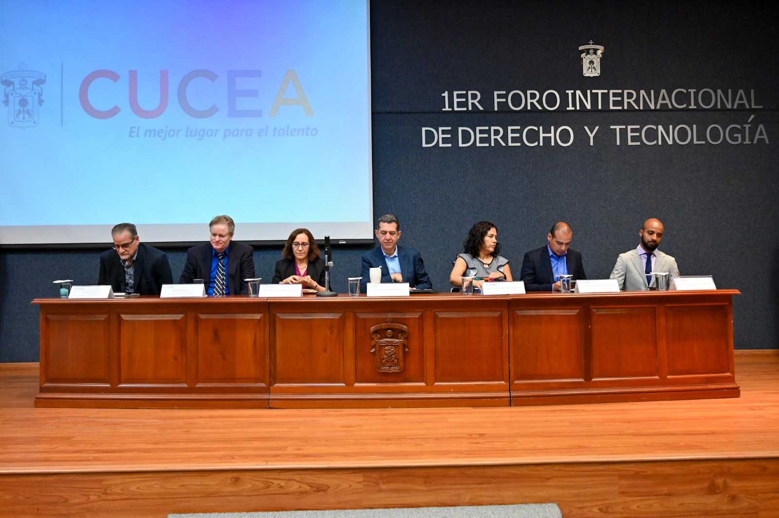 Mesa de siete panelistas con letrero institucional 1ER FORO INTERNACIONAL DE DERECHO Y TECNOLOGÍA
